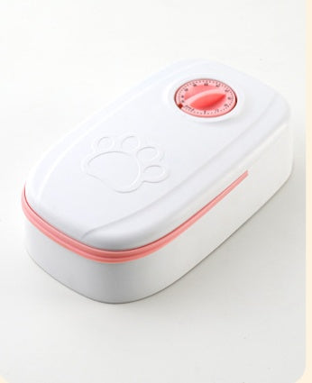 An automatic cat feeder with open lids, showing food, in a stylish, modern indoor setting.