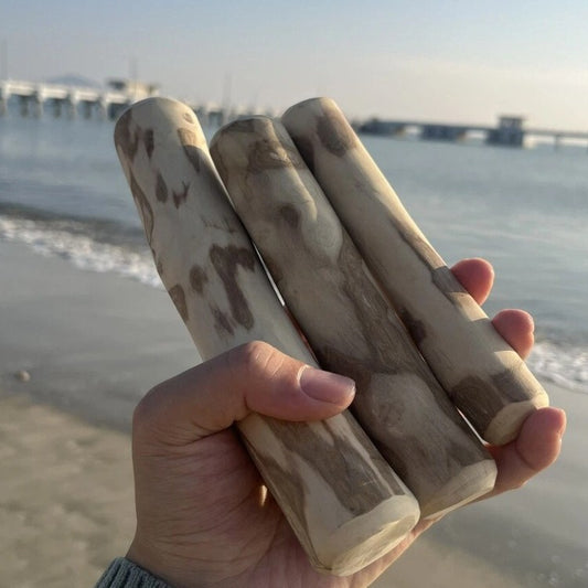 Hand holding four natural coffee wood dog chew sticks showing raw unprocessed wood texture