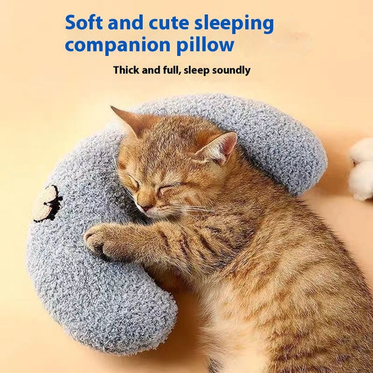 Orange kitten sleeping curled inside grey plush U-shaped neck support pillow, labeled soft and cute sleeping companion pillow