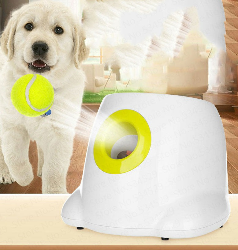 A white automatic ball thrower for dogs with bright yellow accents and tennis balls.