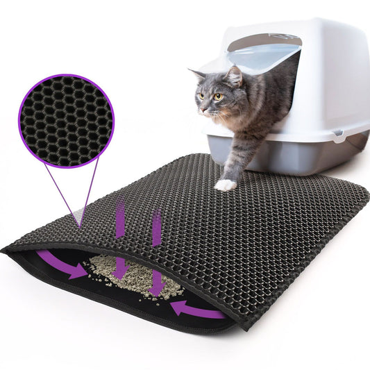 A cat sits beside a textured kitty litter mat showing scattered litter granules.